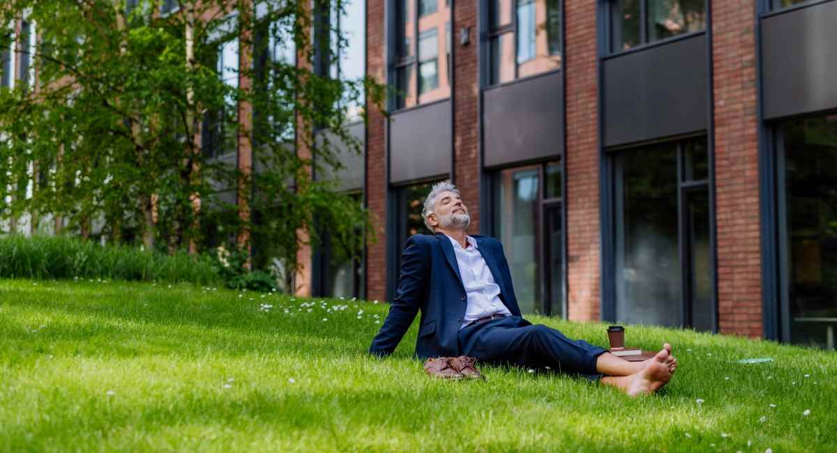 A man in a suit lounging on grass with his shoes off