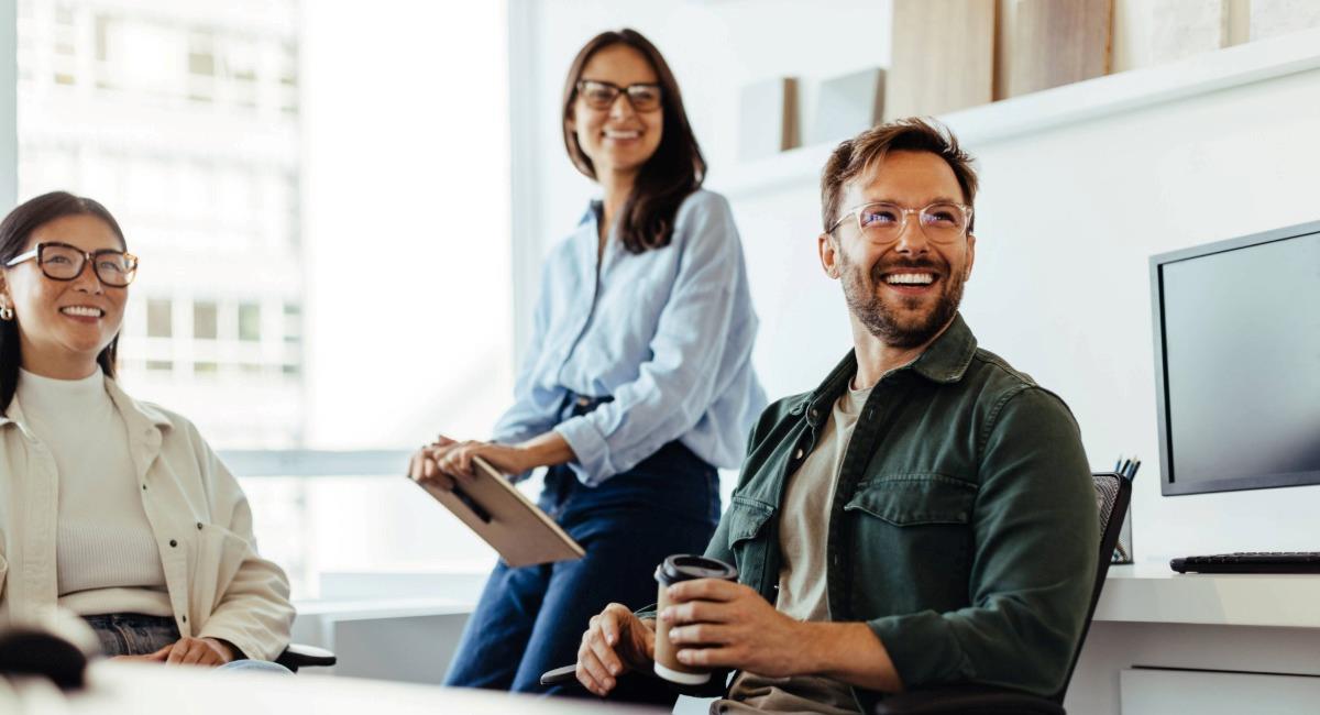 Three young professionals smiling in an office 