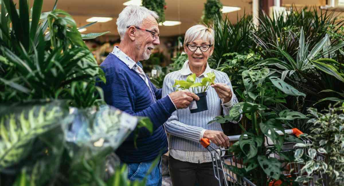 A woman holding a watering can while tending to flowers on a balcony