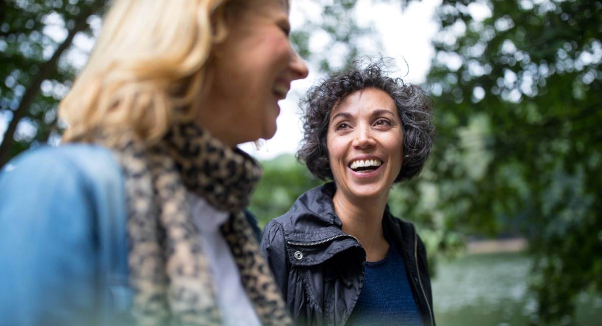 Two middle aged women laughing while out in nature
