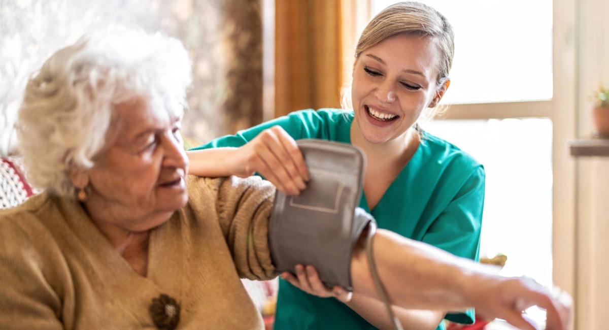 An elderly woman getting her blood pressure checked by a health professional