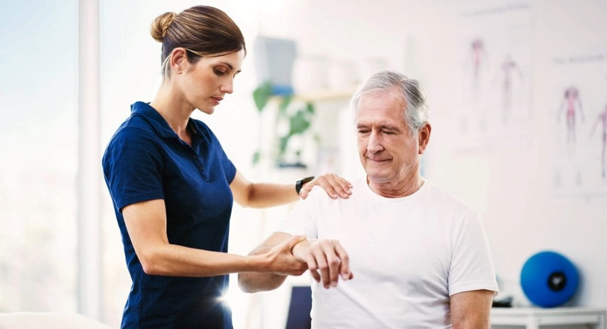 A man inside a physio office receiving treatment from a physio