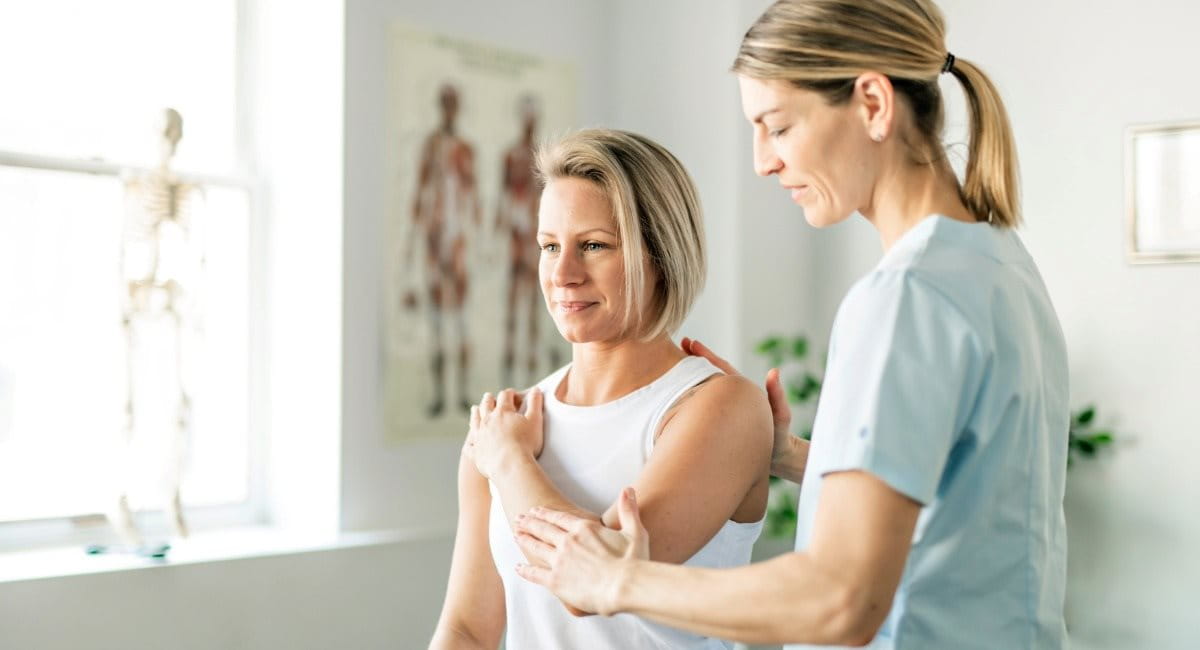A woman receiving shoulder adjustments in a healthcare professional's office