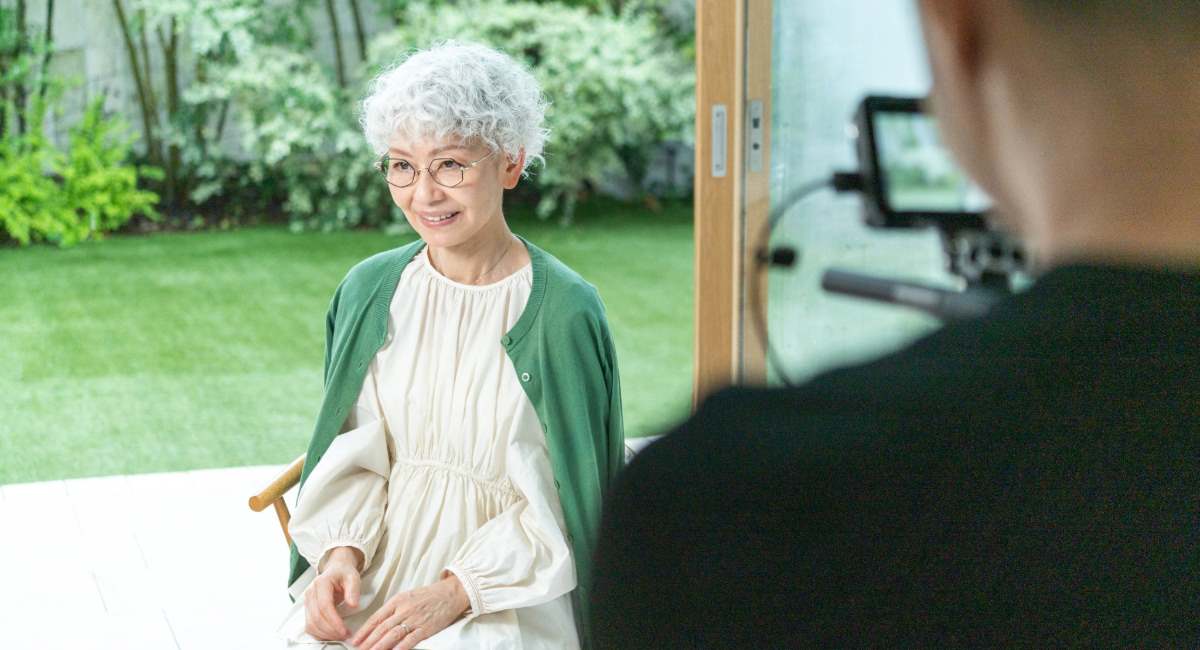 An elderly woman sitting in front of a camera
