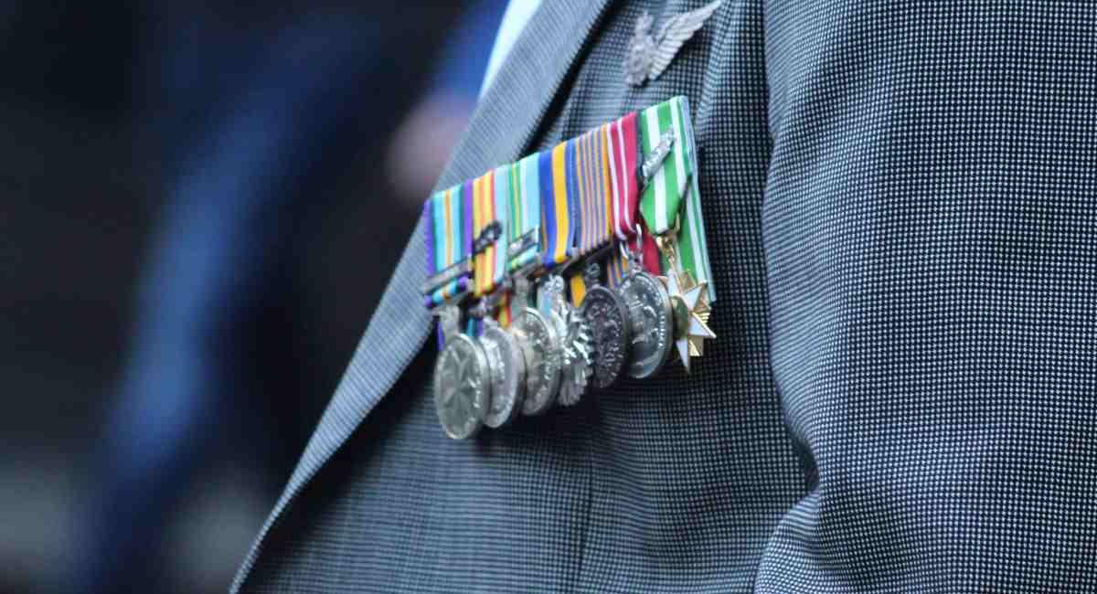 A number of medals on a war veteran's grey jacket