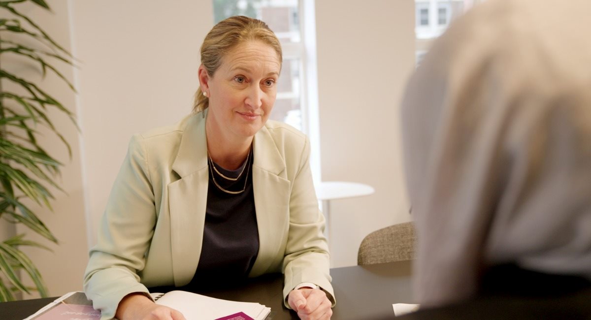 A woman sitting at a desk smiling at a person across from her