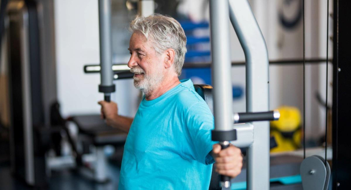 A man with a blue shirt at the gym using gym equipment