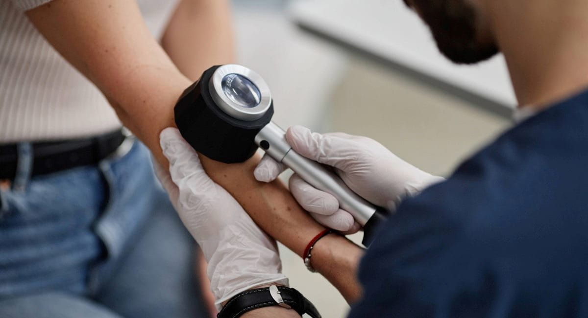 A male doctor inspecting a mole on a young woman's arm