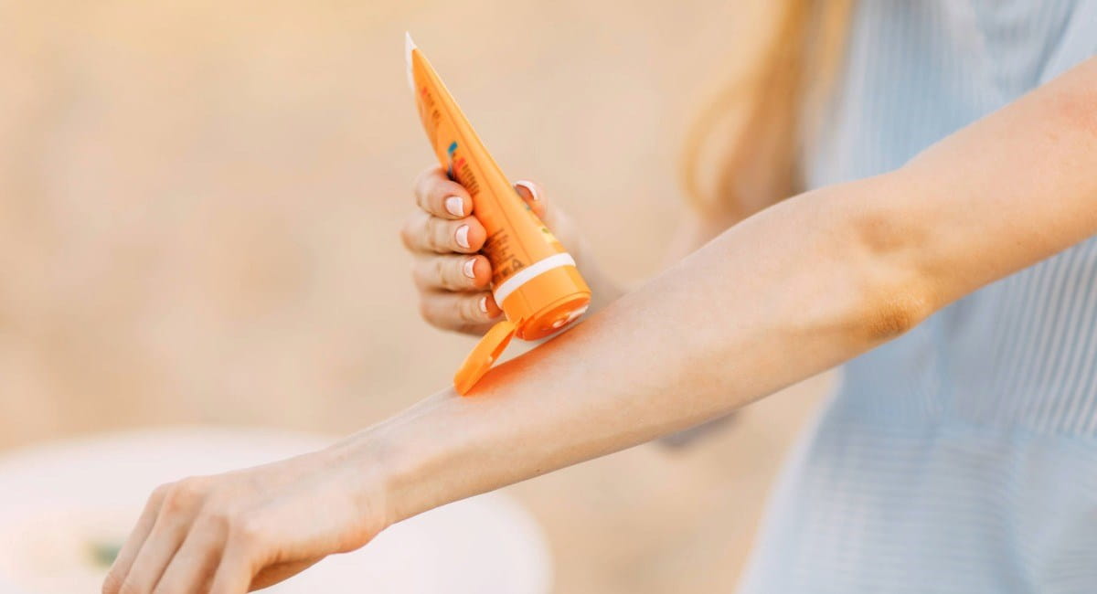 A woman applying sunscreen to her arm