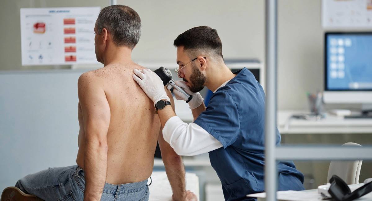 A man receiving a skin cancer check from a doctor in a doctor's office