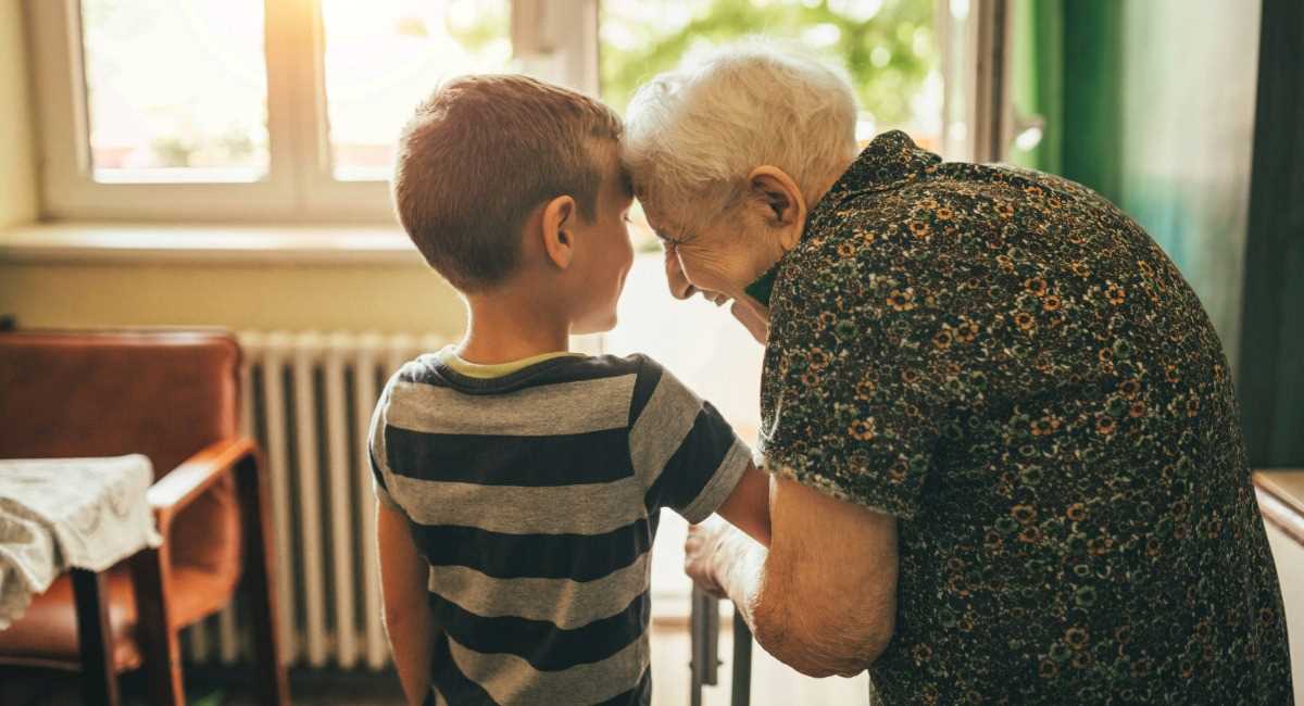 A middle aged woman and her father sitting by the window speaking to each other