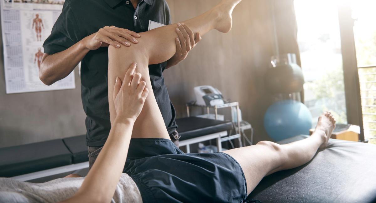 A person laying on a massage bed receiving remedial massage treatment to their knee