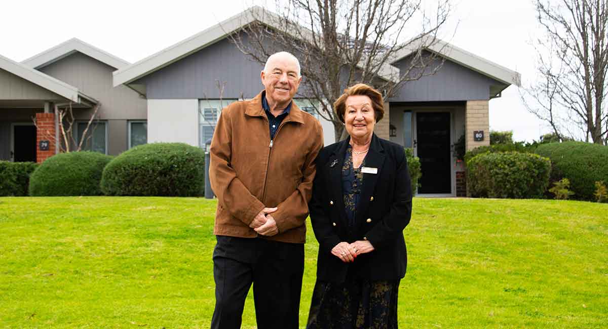 Photo of Kevin and Suzanne La Fontaine, standing in front of their villa at Peninsula Grange Retirement Community.