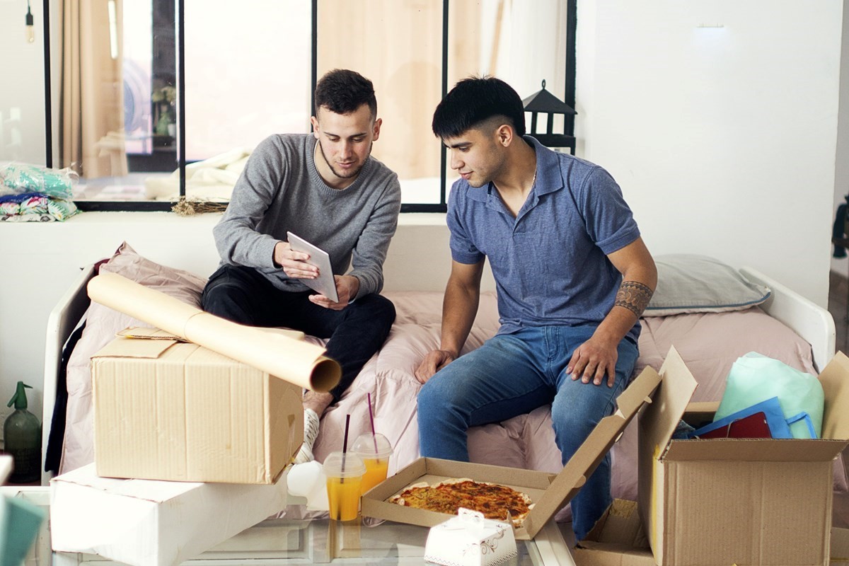 Two men looking at a tablet, surrounded by moving boxes