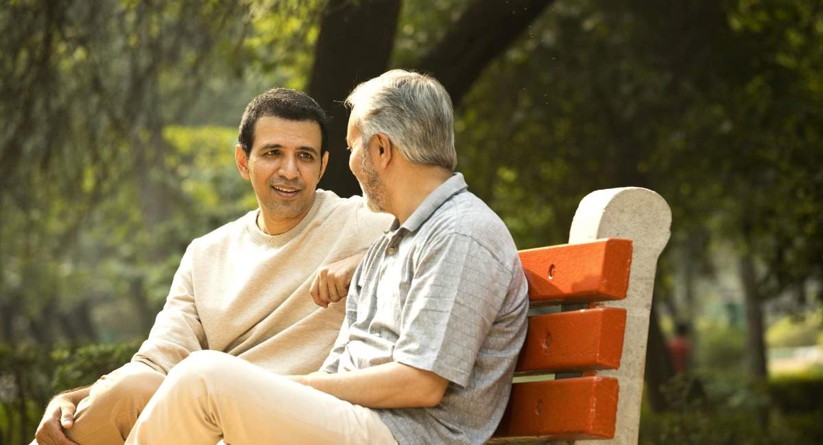 Two men sitting on a park bench while speaking to each other