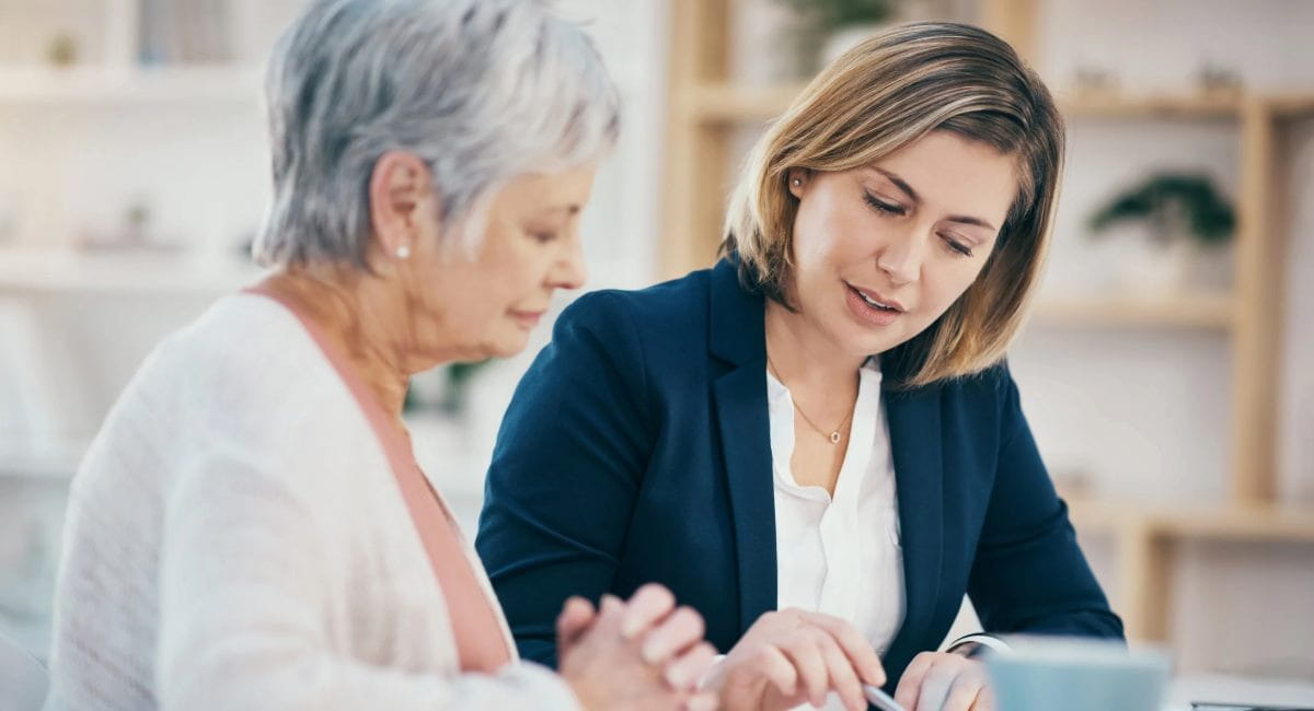 An elderly woman consulting a young professional woman