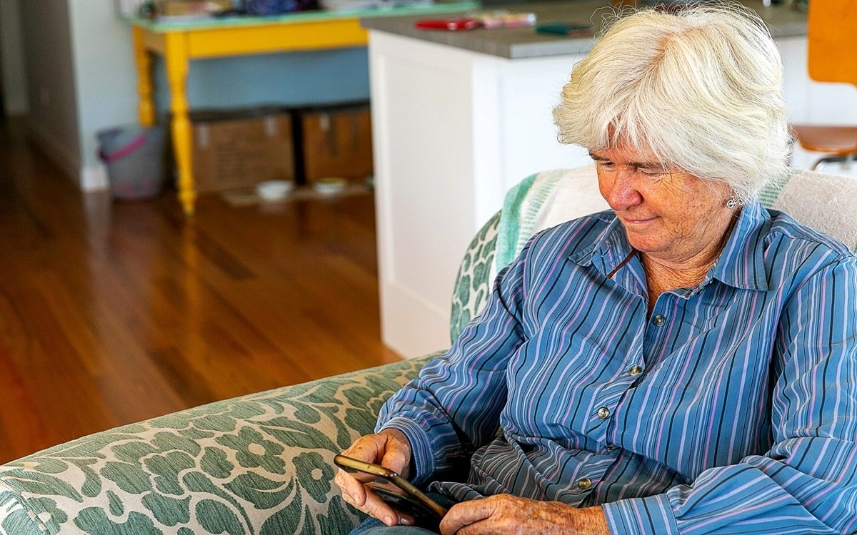 Older woman on couch looking at phone screen
