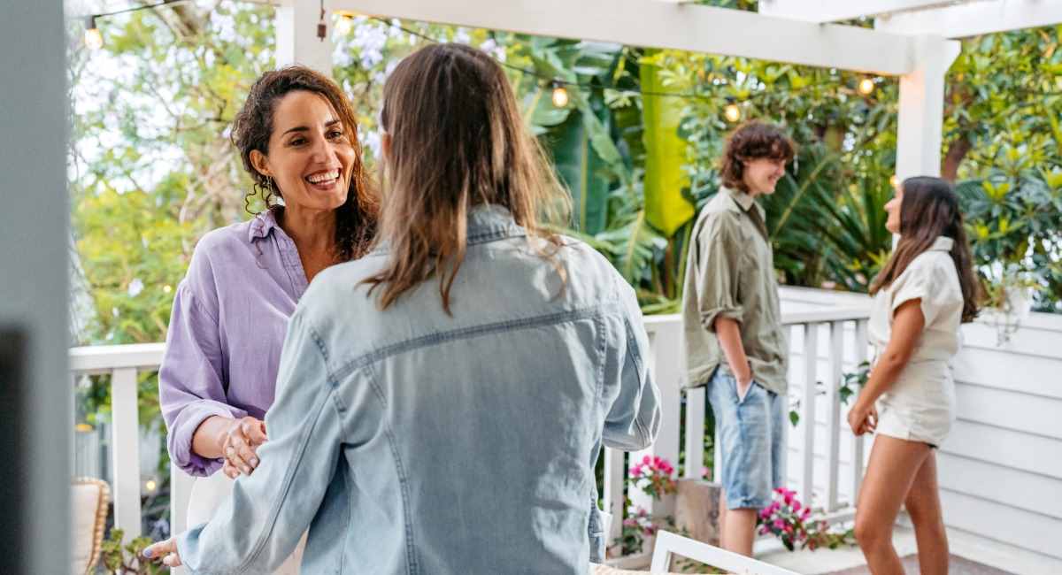 Two groups of young people talking to each other on a leafy white balcony