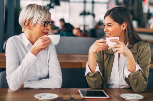 Two smiling women enjoying coffee