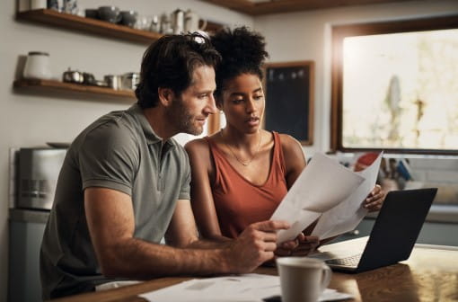 man and woman looking at laptop and finance printouts