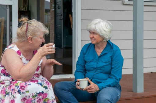 Two older women enjoying a cup of tea on the porch