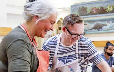 A woman and a man in aprons cooking some food