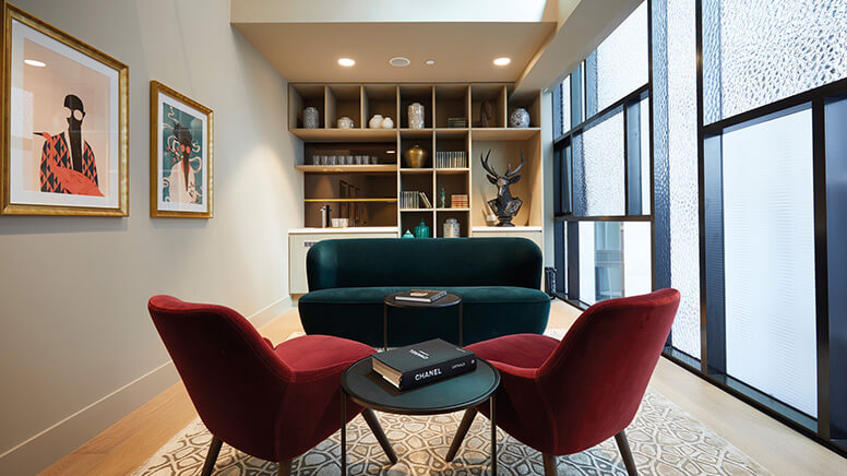 A room with 2 armchairs and 2 seater couch. Bookshelves in the background