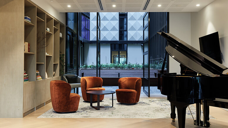 Piano in a room with armchairs around a coffee table